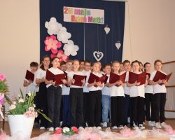 Zdjęcie przedstawia grupę dzieci śpiewających na scenie.